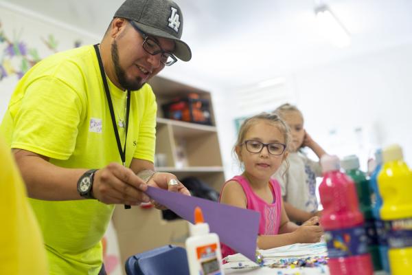 worker helping children with crafts
