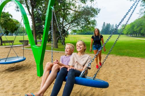 Mother pushing kids on swing