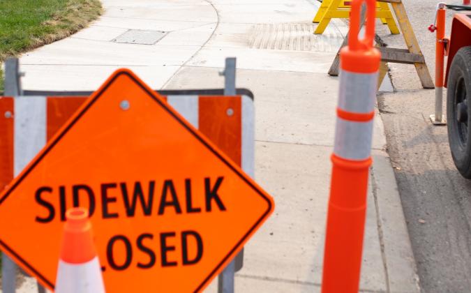 A construction scene in Saskatoon including orange pylons and a "sidewalk closed" sign