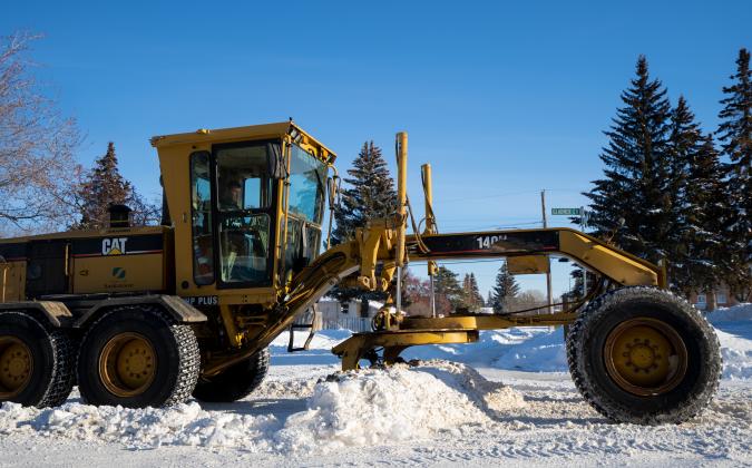 grader plowing snow